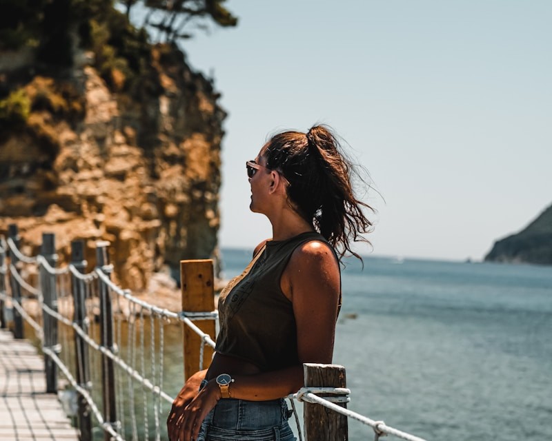 woman in blue denim shorts standing on bridge during daytime